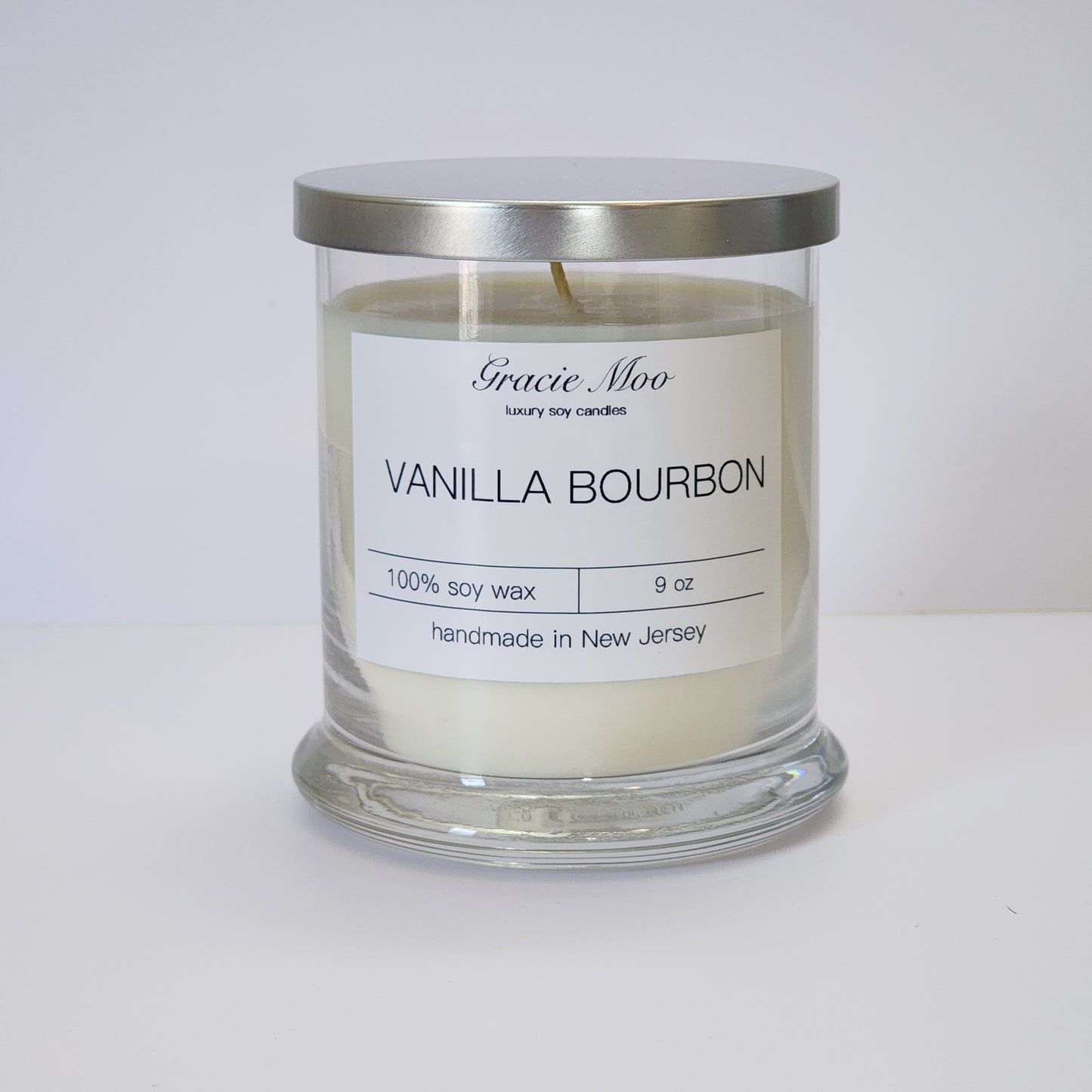 Vanilla Bourbon Status Candle by Gracie Moo Candles in a sleek glass jar with a warm glow, perfect for ambiance.