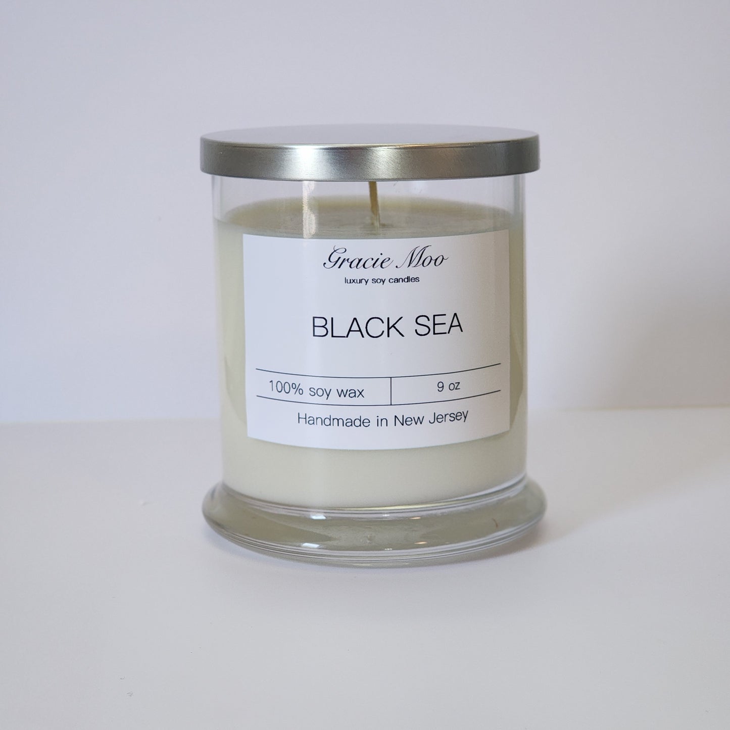 Black Sea Status Candle from Gracie Moo Candles, featuring a sleek black design with a subtle ocean-inspired scent.
