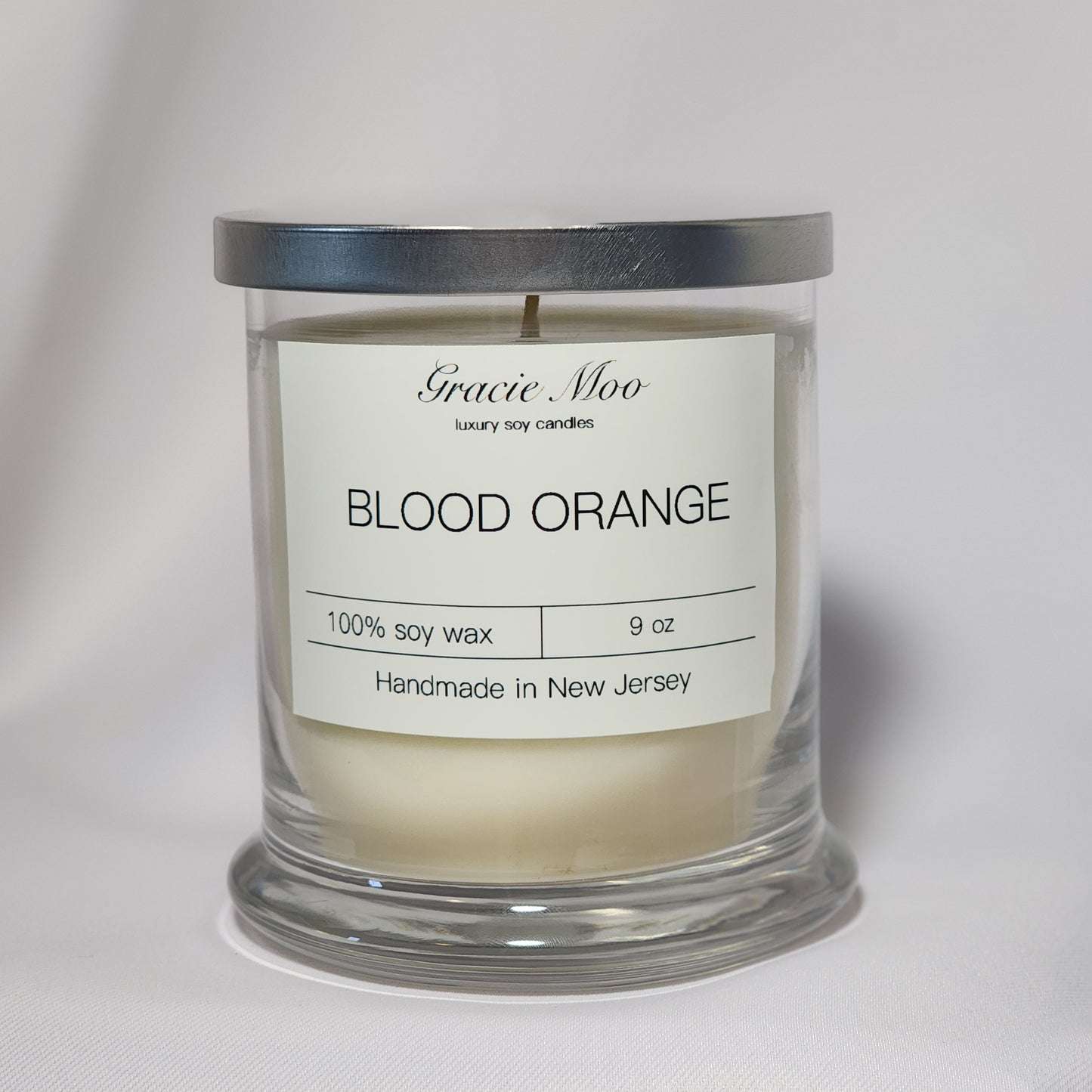 Blood Orange Status Candle by Gracie Moo Candles, featuring a vibrant orange hue and elegant glass container.