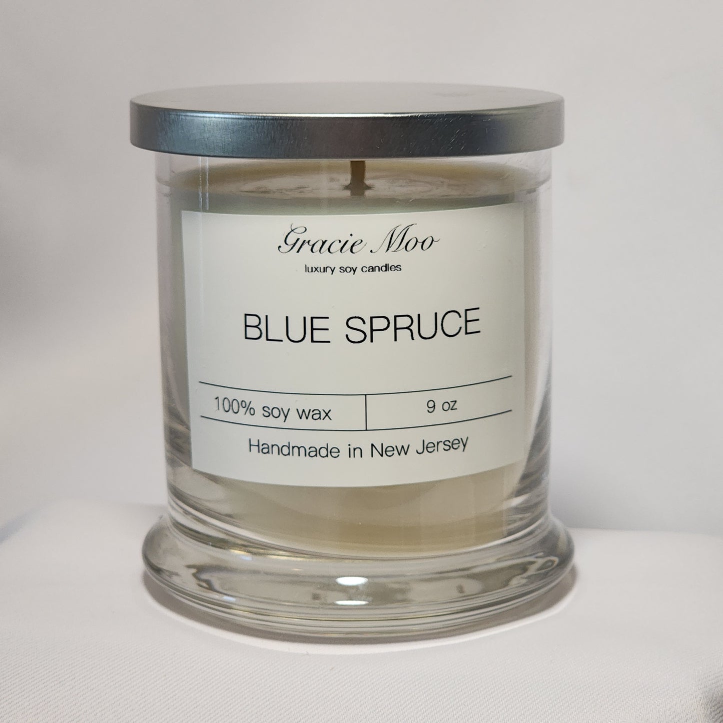 Blue Spruce Status Candle by Gracie Moo Candles, featuring a deep blue color and a sleek glass container.