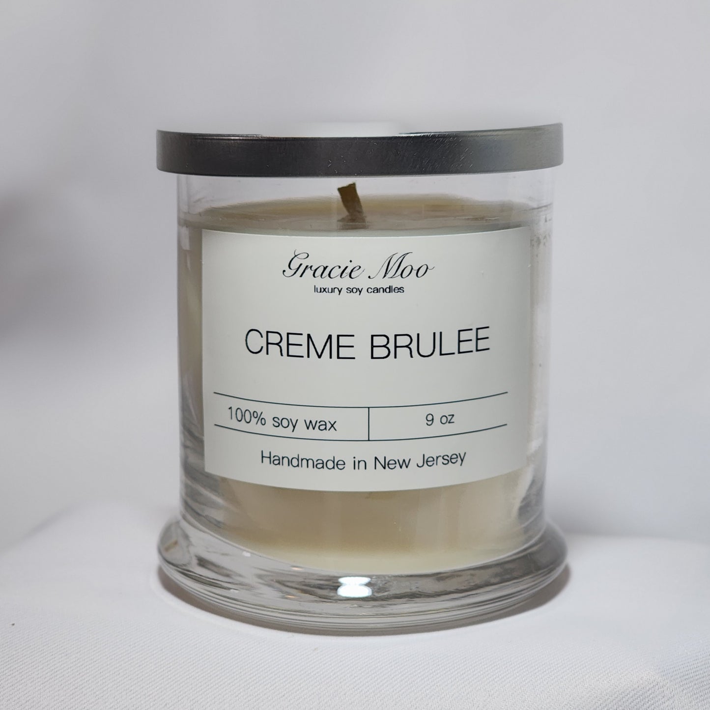 Crème Brûlée Status Candle by Gracie Moo Candles with a creamy texture and caramelized sugar top in a sleek glass jar.
