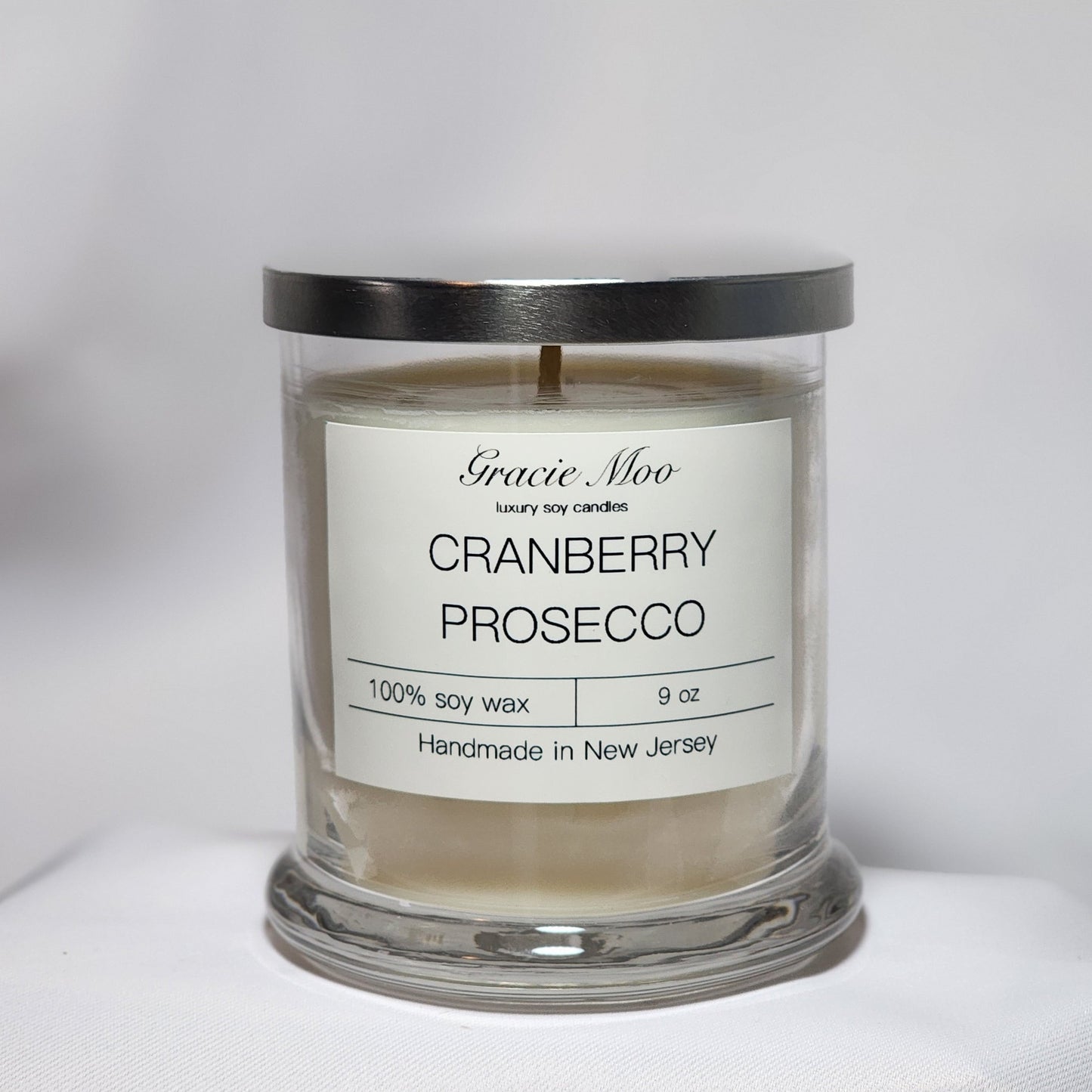 Cranberry Prosecco Status Candle by Gracie Moo Candles with a vibrant red color and elegant glass container.