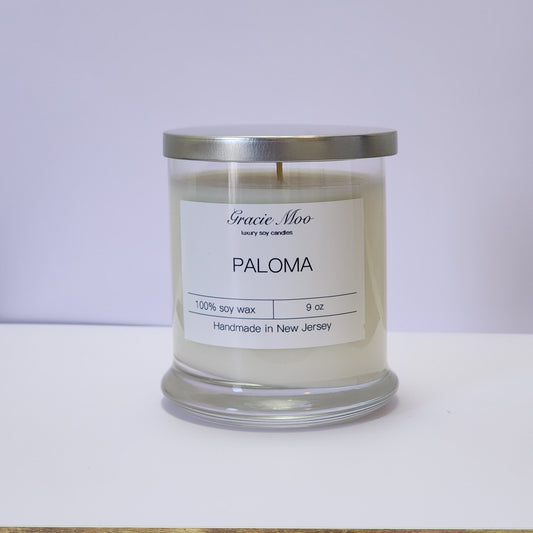 GracieMoo Status Candle in a decorative glass jar with a warm glow, surrounded by soft candlelight ambiance.