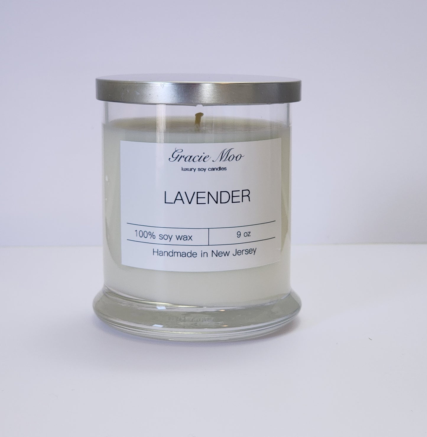 Lavender Status Candle by Gracie Moo Candles featuring a calming lavender hue and elegant glass container.