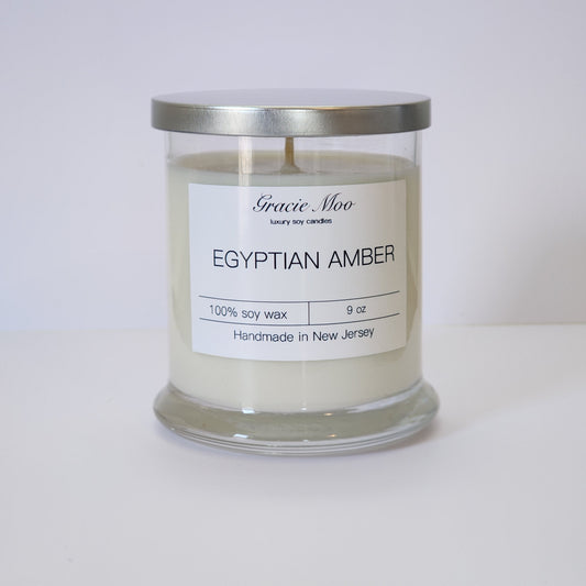 Gracie Moo Candles Egyptian Amber Status Candle with a warm, amber hue and elegant design in a glass jar.