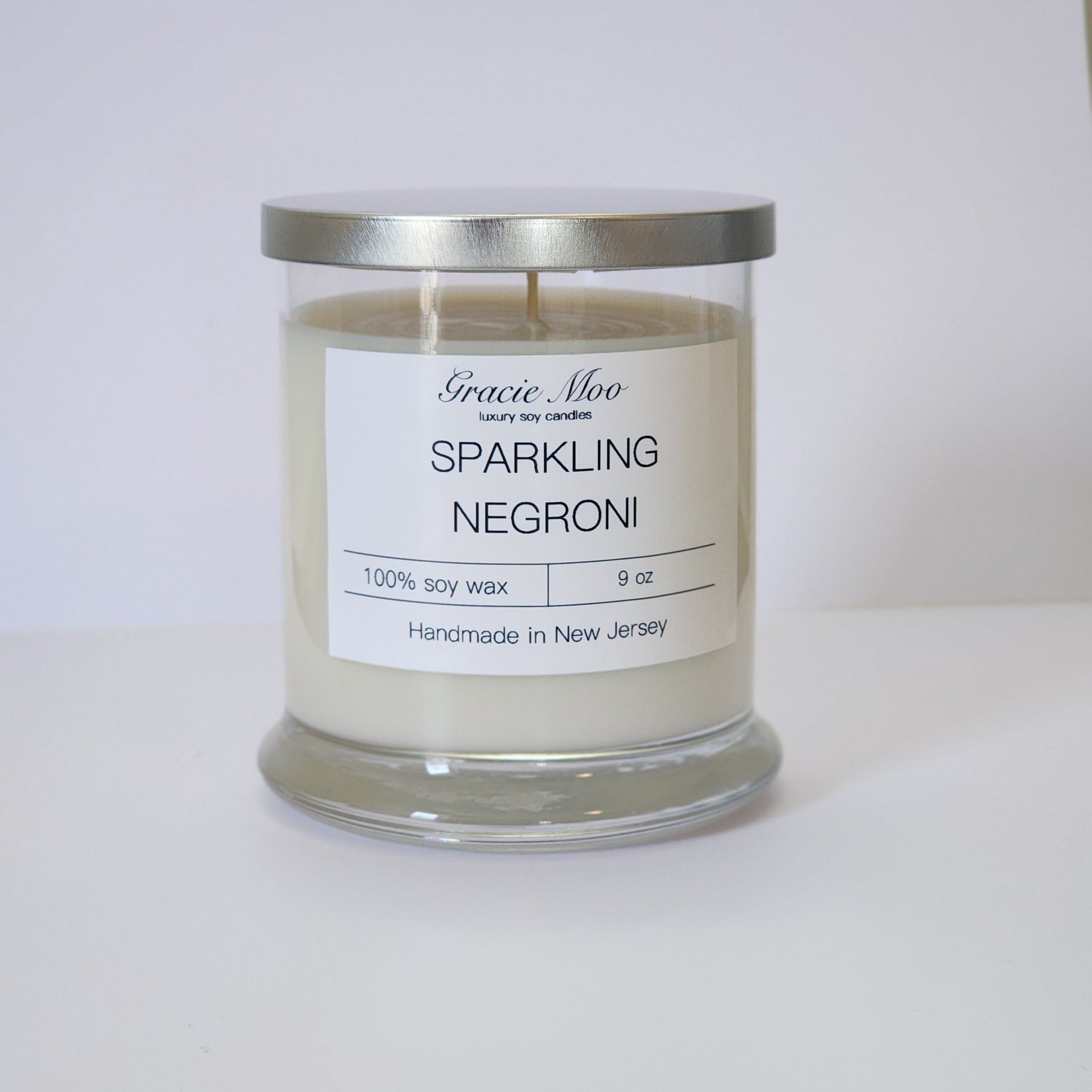 Sparkling Negroni Status Candle by Gracie Moo Candles, featuring a stylish glass container with vibrant candle wax.