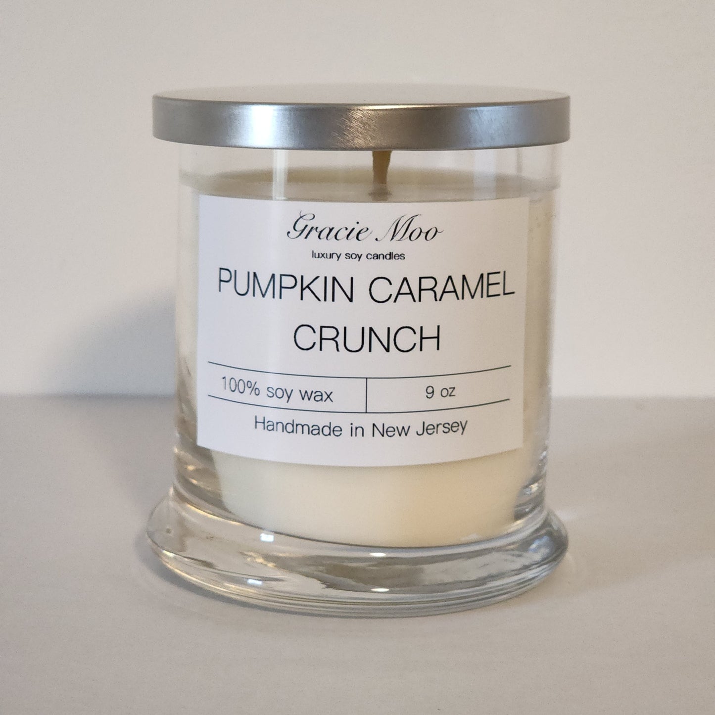 Pumpkin Caramel Crunch candle by Gracie Moo Candles, featuring a warm orange hue and textured surface in a glass jar.