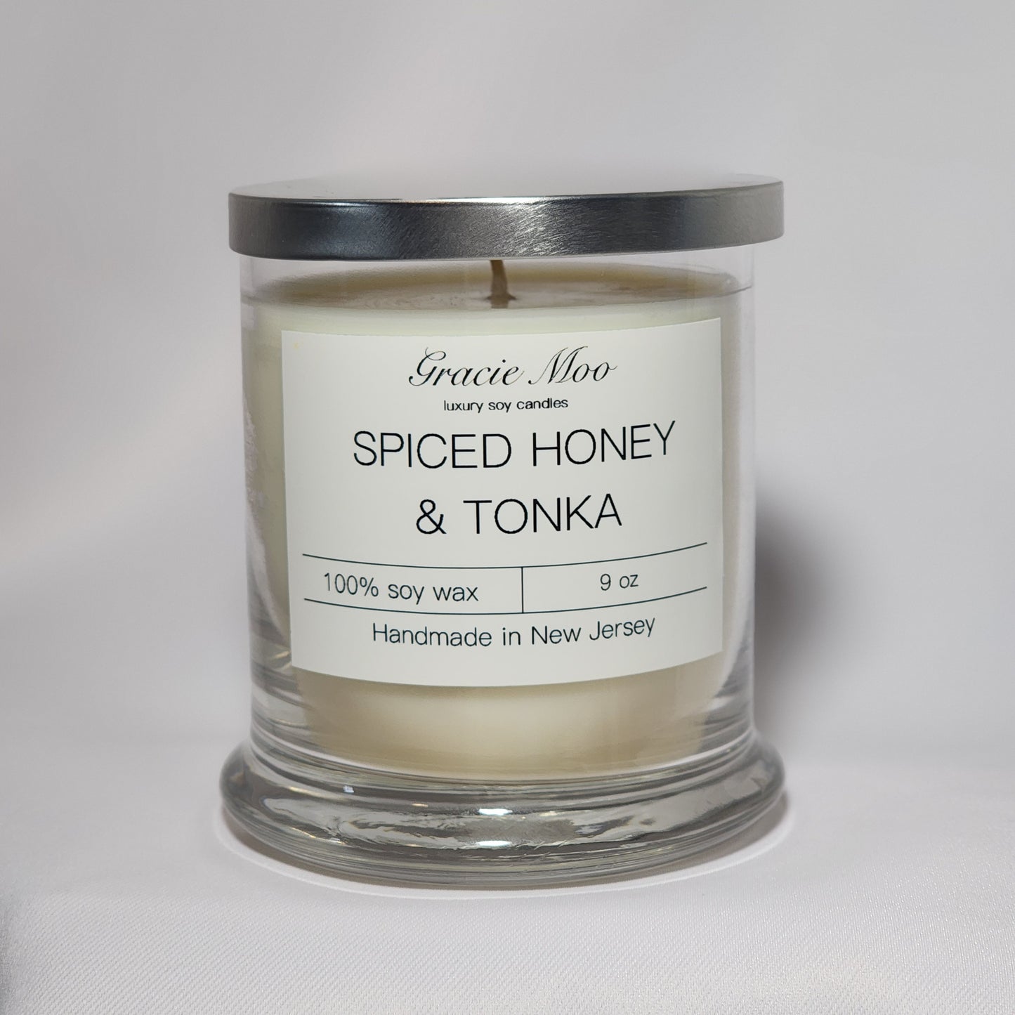 Spiced Honey & Tonka candle by Gracie Moo Candles, showcasing a warm glow with a rustic design in a glass jar.