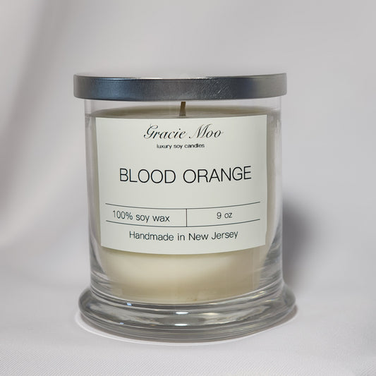 Blood Orange Status Candle by Gracie Moo Candles, featuring a vibrant orange hue and elegant glass container.
