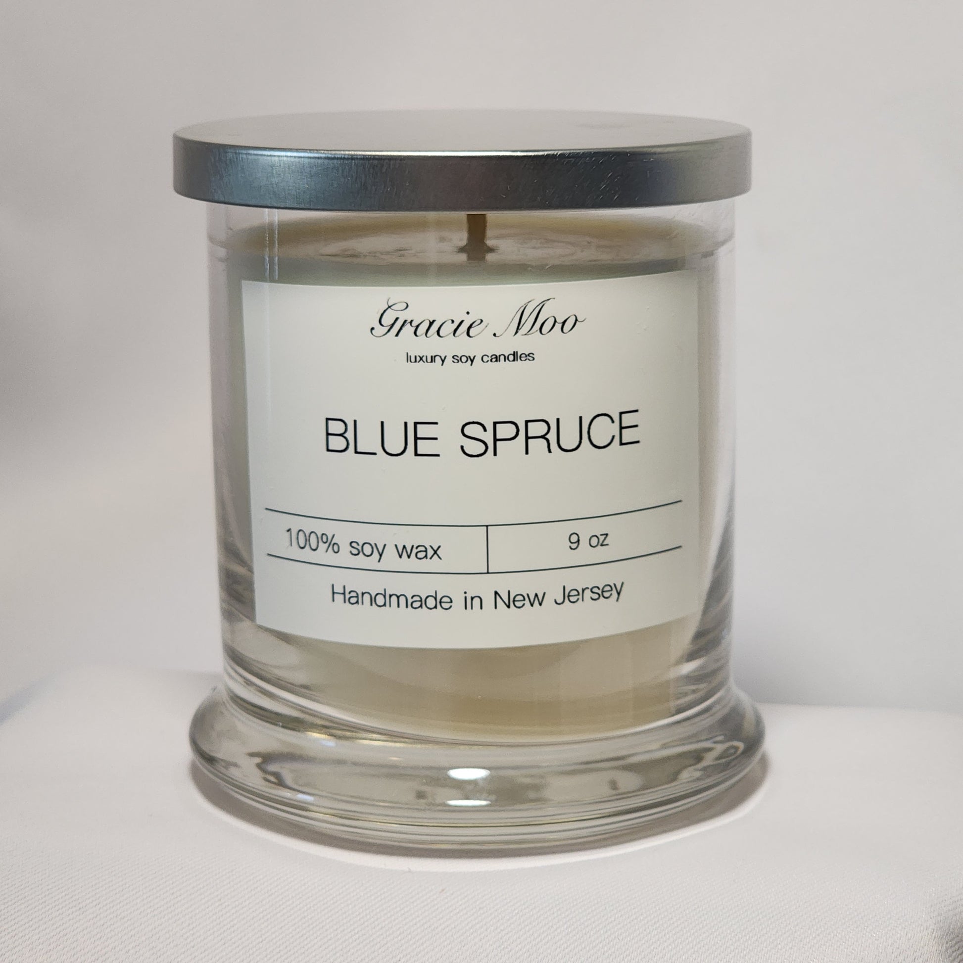 Blue Spruce Status Candle by Gracie Moo Candles, featuring a deep blue color and a sleek glass container.