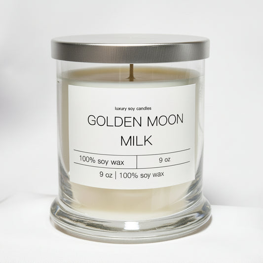 Golden Moon Milk Status Candle by Gracie Moo Candles with a warm glow and decorative label on a wooden surface.