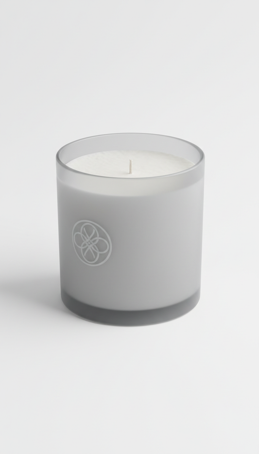 A Gracie Moo Candles scented candle in a glass jar with a lit wick, showcasing warm amber-colored wax and a cozy ambiance setting.
