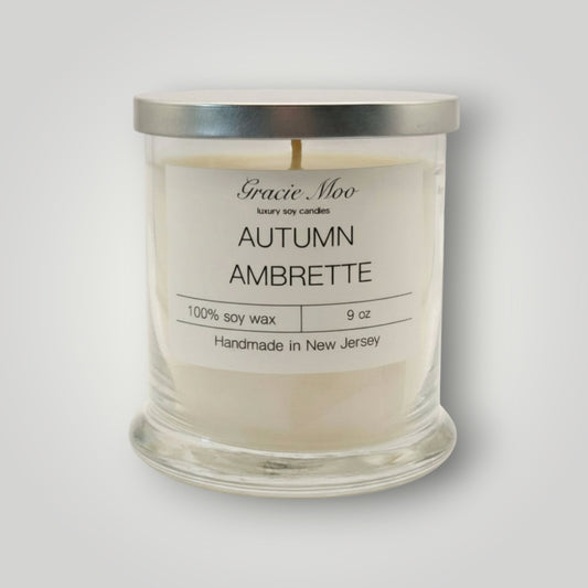 Gracie Moo Autumn Ambrette candle in a glass jar, featuring warm autumn colors and a cozy, inviting design.