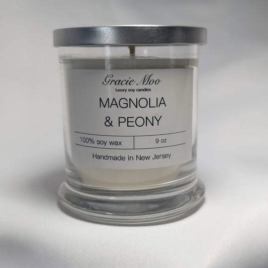 Magnolia and peony scented candle by Gracie Moo Candles in a glass jar with floral design.