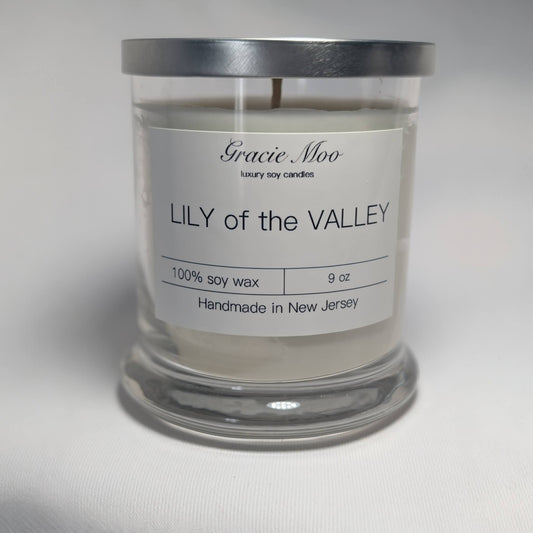 Lily of the Valley scented candle by Gracie Moo Candles, in a decorative glass holder with floral design and white wax.