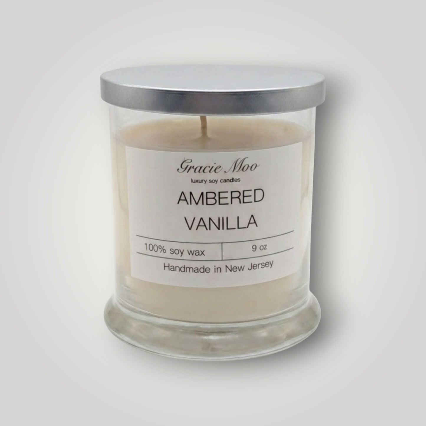 Ambered Vanilla Status Candle by GracieMoo Candles, featuring a warm amber-colored glass container with a lit vanilla-scented flame.