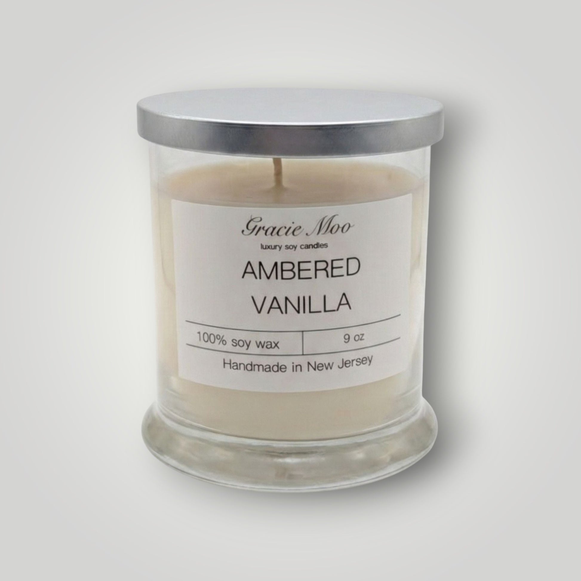 Ambered Vanilla Status Candle by GracieMoo Candles, featuring a warm amber-colored glass container with a lit vanilla-scented flame.