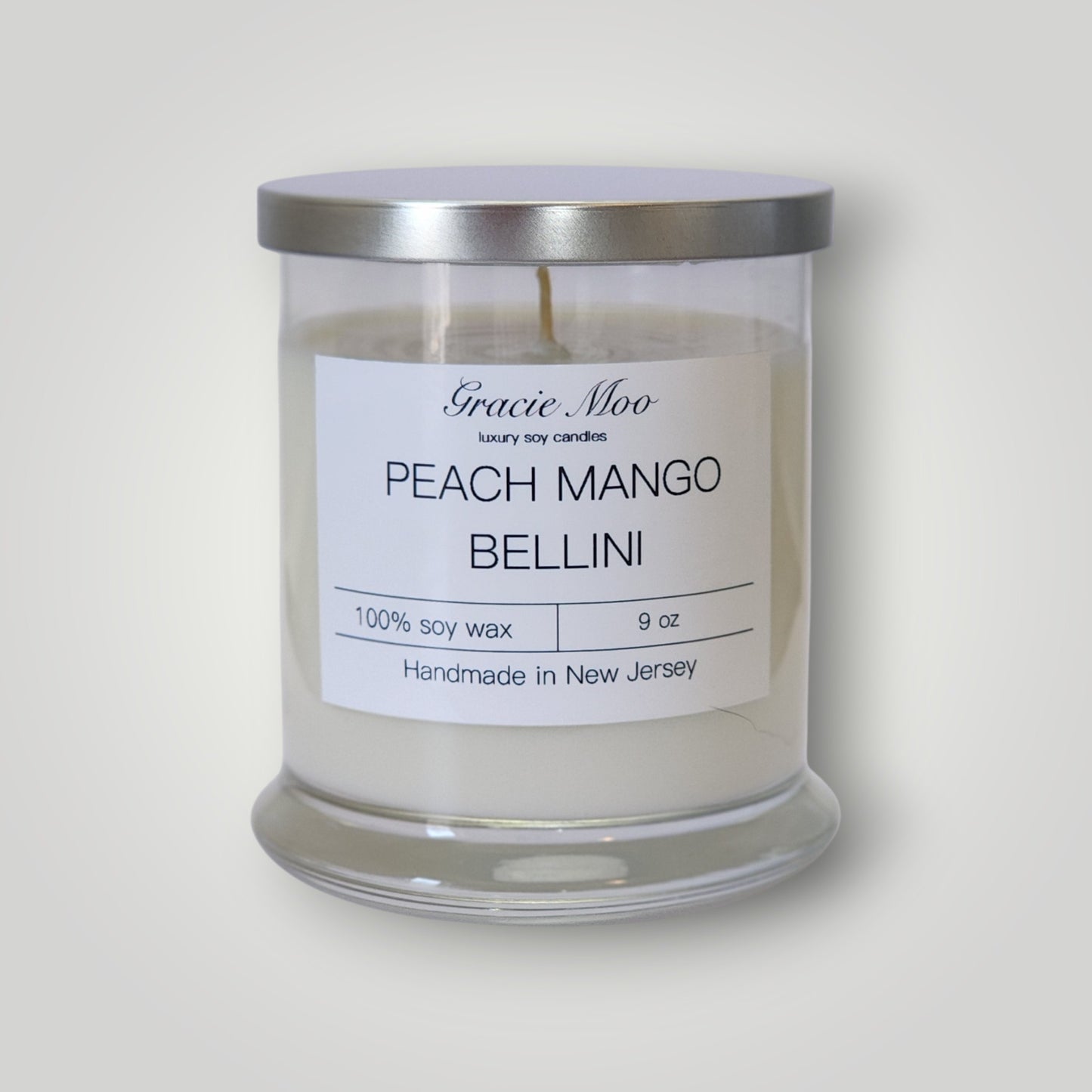 Gracie Moo Candles Peach Mango Bellini scented candle with a stylish glass container and a peach and mango fragrance theme