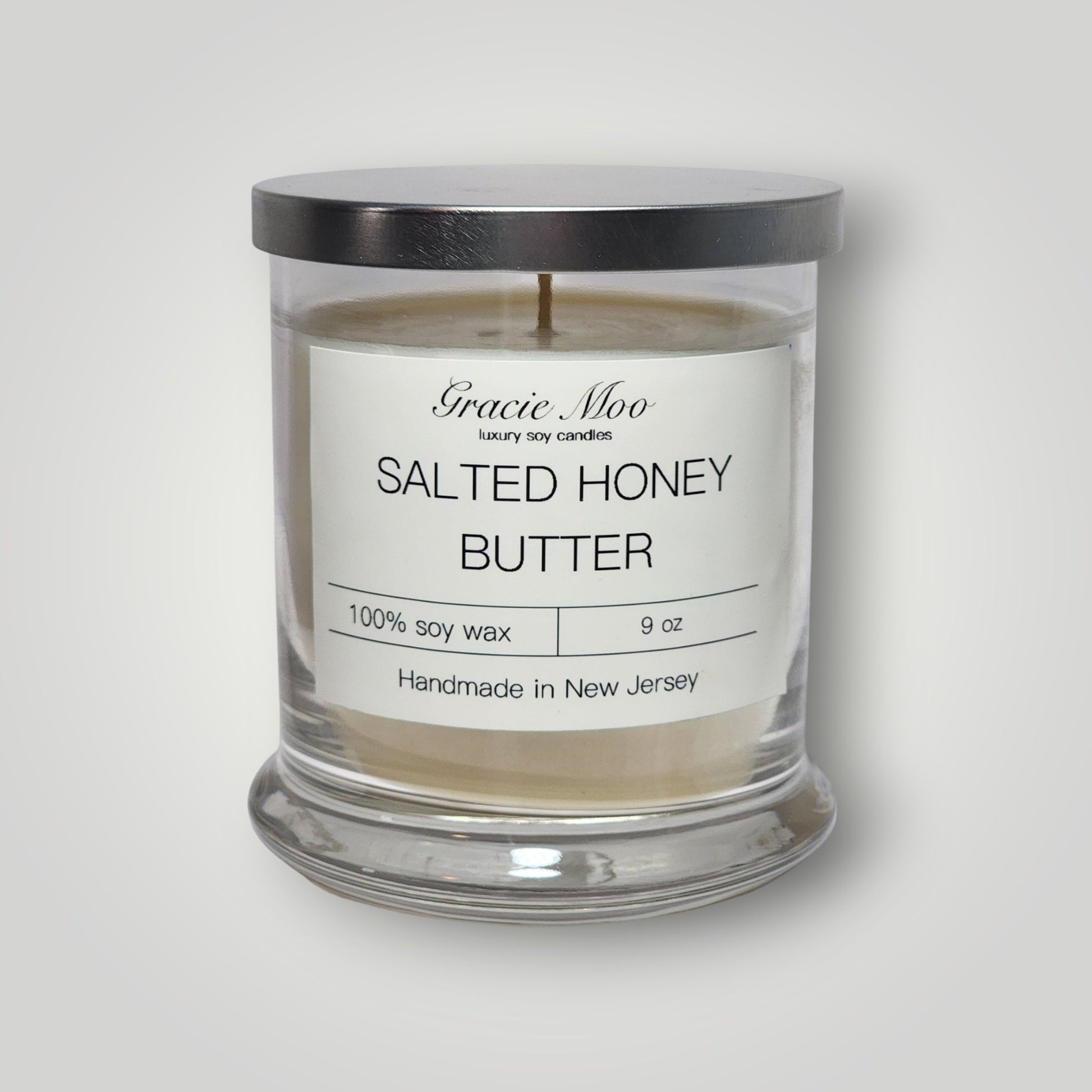 Gracie Moo Candles salted honey butter scented candle in a glass jar with a wooden wick and warm, inviting glow.